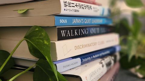 Books on a shelf with plants.